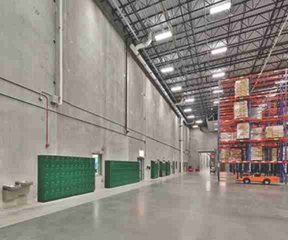 A newly constructed precast concrete warehouse with shelves packed with merchandise.