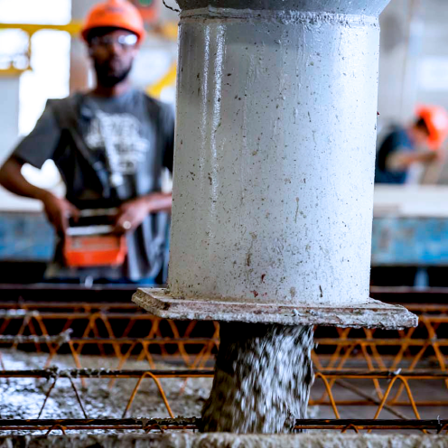Wet concrete being poured into a mold. An employee is working in the background.